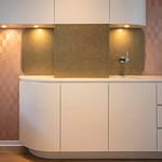 repräsentatives Behandlungszimmer mit Behandlungsstuhl und Einbaumöbeln in weiß und goldfarbenen Akzenten und roséfarbener Tapete Insignia von Arte Praxis-Design in der Praxis für Ästhetische Medizin Dr. med. Eveline Urselmann Milchstrasse 26 bis 28 Hamburg Pöseldorf Rotherbaum im ästhetischen und zeitlosen Design von Lange Architekten