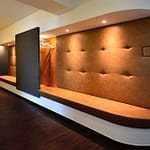 repräsentativer Empfangsbereich und Wartebereich mit großer brauner Leder Sitzfläche und gesteppter Leder Rückwand und Garderobe Praxis-Design in der Praxis für Dermatologie Venerologie und TCM Dr. med. May Sian Oei Schillerstr. 44b Ottensen im ästhetischen und zeitlosen Design von Lange Architekten