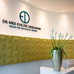 repräsentativer Empfangsbereich und Empfangs-Tresen aus Corian weiß geschwungene organisch geformte Wände mit senf-gelben Wandornamenten Wandrelief von Arte Praxis-Design in der Praxis für Ästhetische Medizin Dr. med. Eveline Urselmann Milchstrasse 26 bis 28 Hamburg Pöseldorf Rotherbaum im ästhetischen und zeitlosen Design von Lange Architekten
