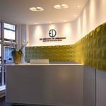 repräsentativer Empfangsbereich und Empfangs-Tresen aus Corian weiß geschwungene organisch geformte Wände mit senf-gelben Wandornamenten Wandrelief von Arte Praxis-Design in der Praxis für Ästhetische Medizin Dr. med. Eveline Urselmann Milchstrasse 26 bis 28 Hamburg Pöseldorf Rotherbaum im ästhetischen und zeitlosen Design von Lange Architekten