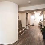 Arztpraxis-Design Empfangsbereich und Tresen in der Chiropractic West von Chiropractor Corinna Haack im ästhetischen Spa Design mit geschwungenen Wänden und geschwungenen Möbeln und Produkt-Design mit dunklen Holz-Lamellen zum Wohlbefinden der Kunden