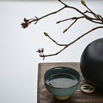 Tea Passion_Sven-Christian Lange_Branding Photography_Black Cast Iron Vase And Branch With Buds With Turquoise Matcha Bowl On Ancient Wooden Stand_Tea Ceremony_Wabi Sabi