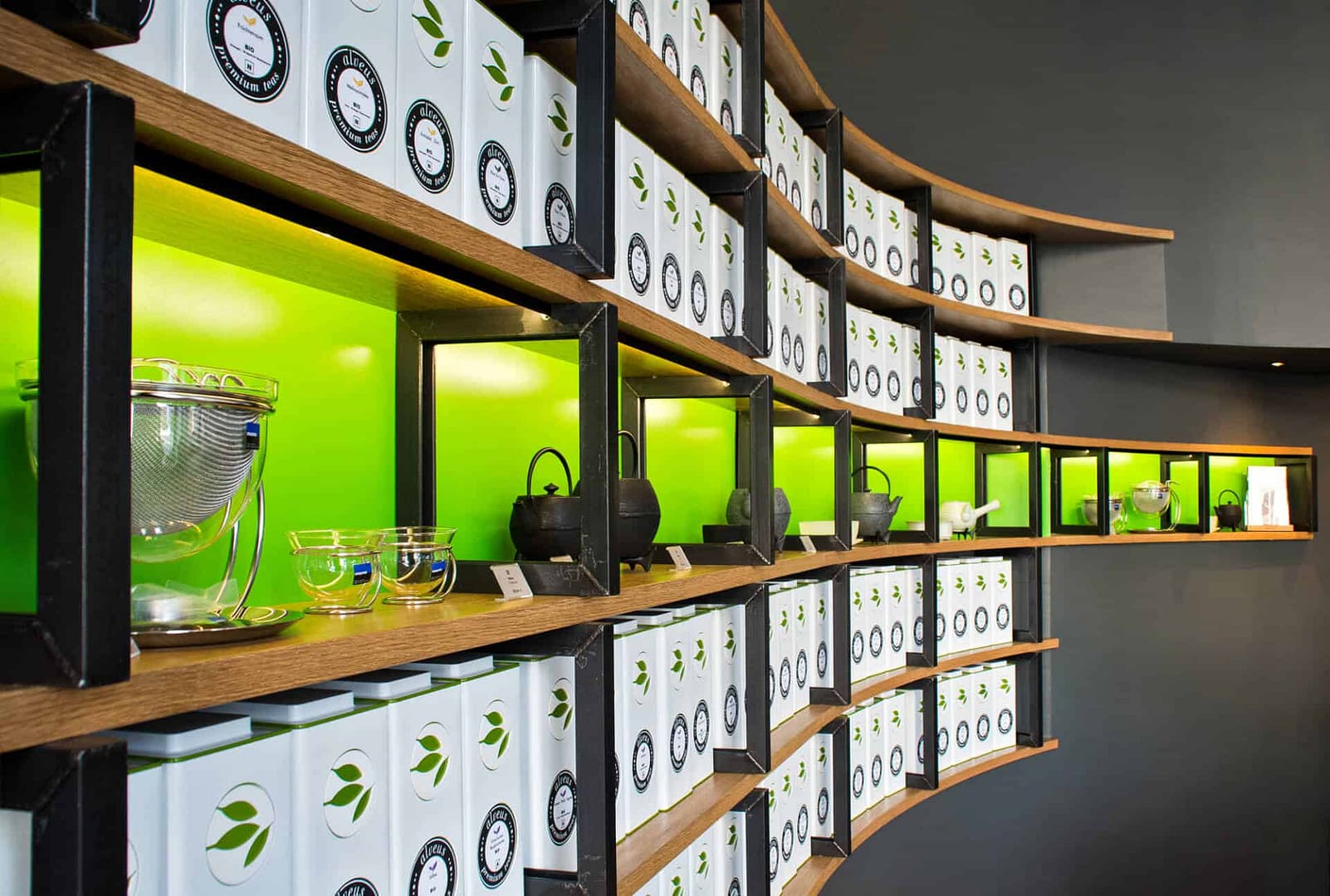 perfektes und funktionales Tee Store Konzept Retail-Design Produkt-Design Corporate-Design von Lange Architekten im ersten alveus Bio-Tee Tea-Store Alster mit Akzenten in Eichenholz und Stahl mit repräsentativer organischer Rückwand mit alveus Caddies und Logo creates-your-premium-tea in den Colonnaden Hamburg