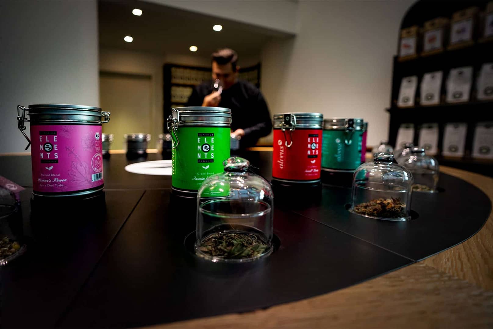 perfektes organisches und funktionales Tee Store Konzept Retail-Design Produkt-Design Corporate-Design von Lange Architekten im weißen alveus Bio-Tee Tea-Store mit Akzenten in Eichenholz und Stahl mit zentralem Probier-Tresen in der HafenCity Hamburg unweit der Elbphilharmonie