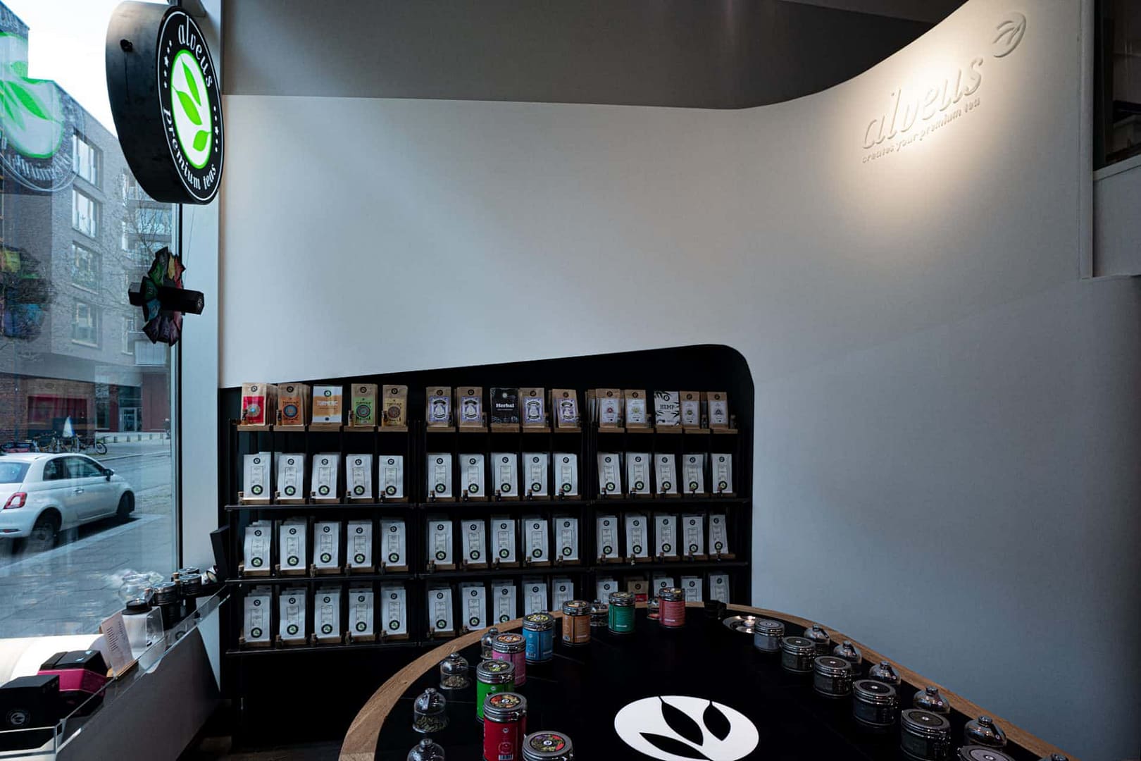 perfektes organisches und funktionales Tee Store Konzept Retail-Design Produkt-Design Corporate-Design von Lange Architekten im weißen alveus Bio-Tee Tea-Store mit Akzenten in Eichenholz und Stahl mit Probier-Tresen und Tee-Regalen und Schaufenster-Dekoration in der HafenCity Hamburg unweit der Elbphilharmonie