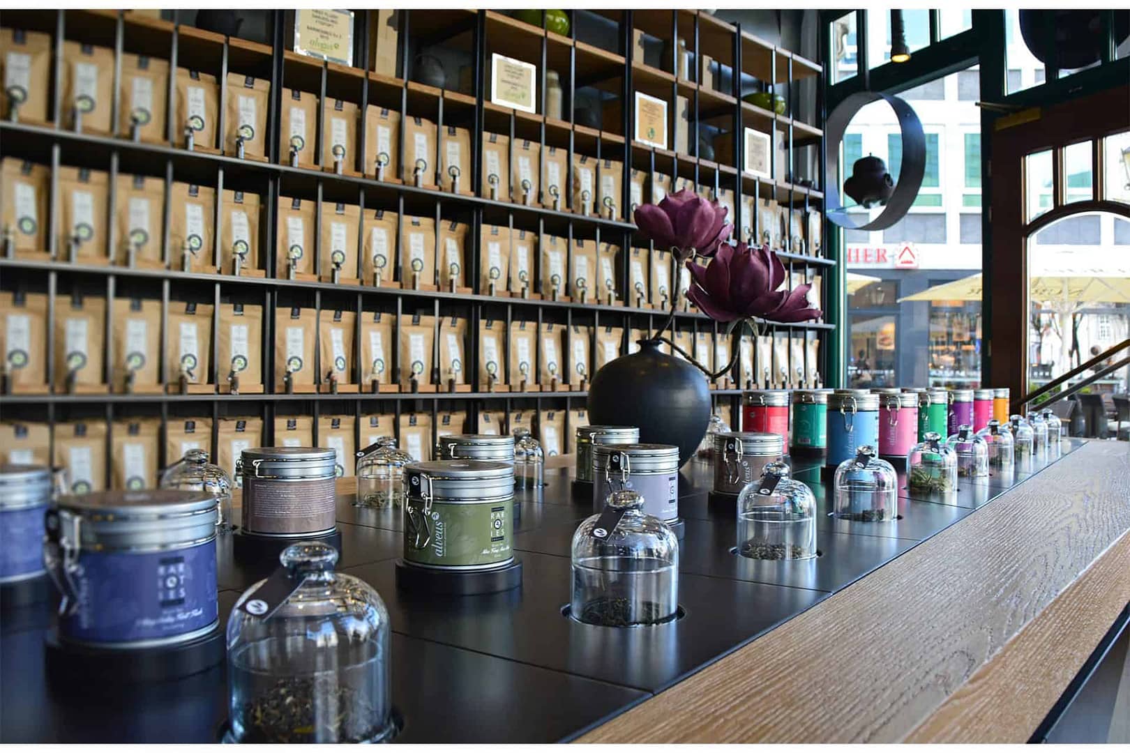 perfektes und funktionales Tee Store Konzept Retail-Design Produkt-Design Corporate-Design von Lange Architekten im ersten alveus Bio-Tee Tea-Store Alster mit Akzenten in Eichenholz und Stahl mit Probier-Tresen und Tee-Regalen mit Tester-Gläsern in den Colonnaden Hamburg