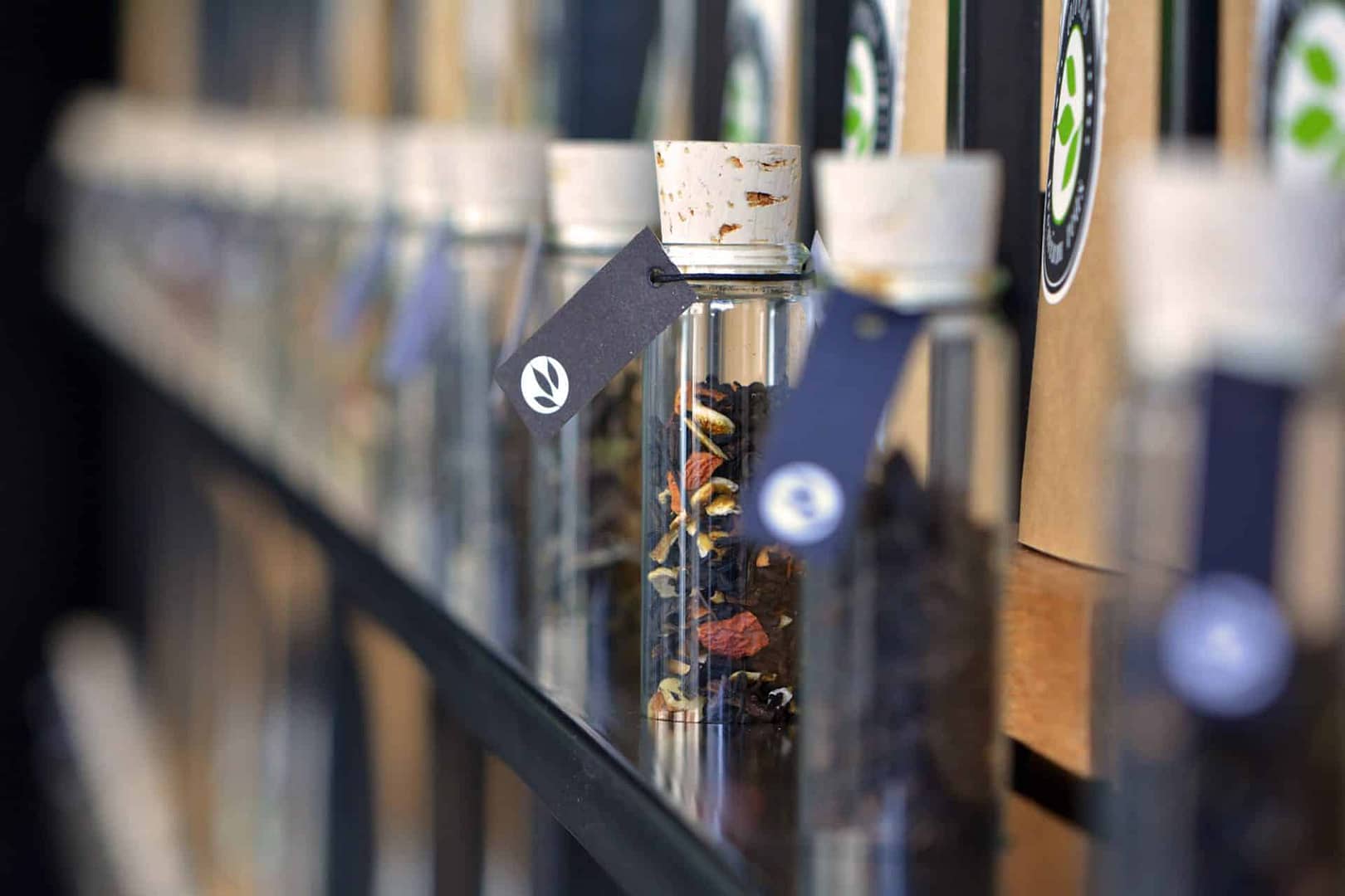 perfektes und funktionales Tee Store Konzept Retail-Design Produkt-Design Corporate-Design von Lange Architekten im ersten alveus Bio-Tee Tea-Store Alster mit Akzenten in Eichenholz und Stahl mit Tee-Regalen mit Tester-Gläsern als Tee Einkaufserlebnis in den Colonnaden Hamburg