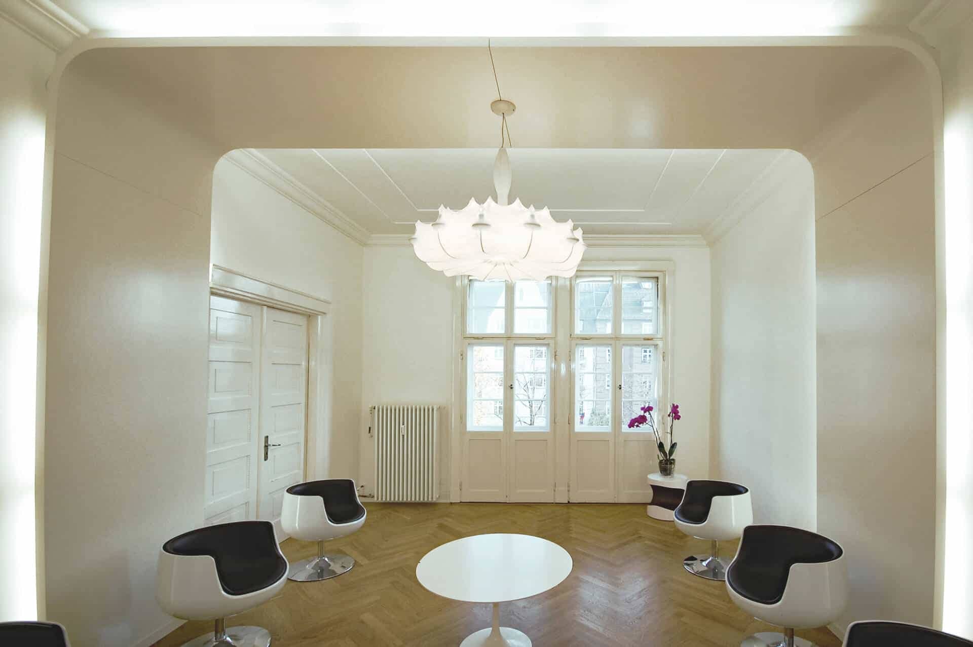 weißes Wartezimmer mit beleuchteter Schrankwand Hochglanz weiß mit Rost-Optik und Pendelleuchte Tobias Grau Falling Water und Flos Zeppelin und Raumteiler Praxis-Design in der Praxis Frauenaerztin am Rothenbaum Dipl. med. Tatjana Swirski Curiohaus Rothenbaumchaussee Hamburg Harvestehude im ästhetischen und zeitlosen Design von Lange Architekten